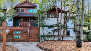 A cabin-style building with a wooden exterior, a porch, and a staircase leading to the entrance. - Ski In/Out| Combined Upper and Lower Unit 780/781 | 5 Bedroom | Gas Fireplace (Boyne Fallss)
