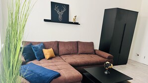 A modern living room with a brown sectional sofa, a black coffee table, and a potted plant.
