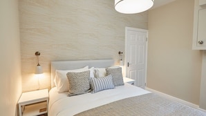 A neatly arranged bedroom with a large bed, two bedside tables, and a door. - Host & Stay | Silver Beach (Whitby)