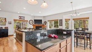 A spacious kitchen with a large island, wooden cabinets, and a dining area with a high table and chairs. - Doc's Place (Leadville)