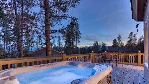 A hot tub on a wooden deck with a view of trees and mountains. - Doc's Place (Leadville)