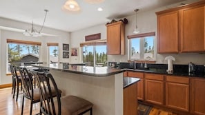 A modern kitchen with a central island, wooden cabinets, and a bar seating area. - Doc's Place (Leadville)