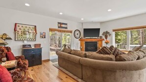 A living room with a fireplace, a large window, and a wall-mounted clock. - Doc's Place (Leadville)