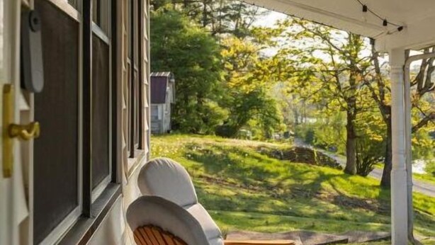 Een veranda met twee houten schommelstoelen en uitzicht op een groen landschap.