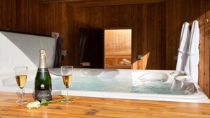 A wooden cabin with a hot tub, a bottle of champagne, and two glasses on a wooden table. - Two Queens Houses -  a house that sleeps 10 guests  in 5 bedrooms (Aviemore)