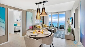 Une chambre d’hôtel moderne dotée d’un coin repas, d’un balcon avec vue sur la mer et d’une grande fenêtre.