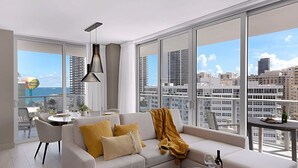 A modern living room with a sofa, a table, and a chair. Large windows offer a view of the cityscape. - Wrap Around Balcony|Insane Amenities+ Amazing Pool (Hollywood)