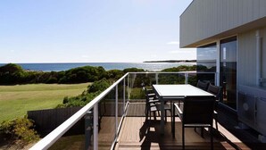 Une terrasse avec une table et des chaises donnant sur un paysage côtier.