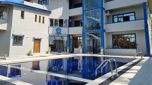 A modern hotel with a swimming pool, multiple balconies, and a central entrance with a logo. - Dhammika Beach Palace (Wadduwa)