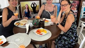 A dining table with plates of food, glasses of orange juice, and a framed picture on the wall. - Dhammika Beach Palace (Wadduwa)