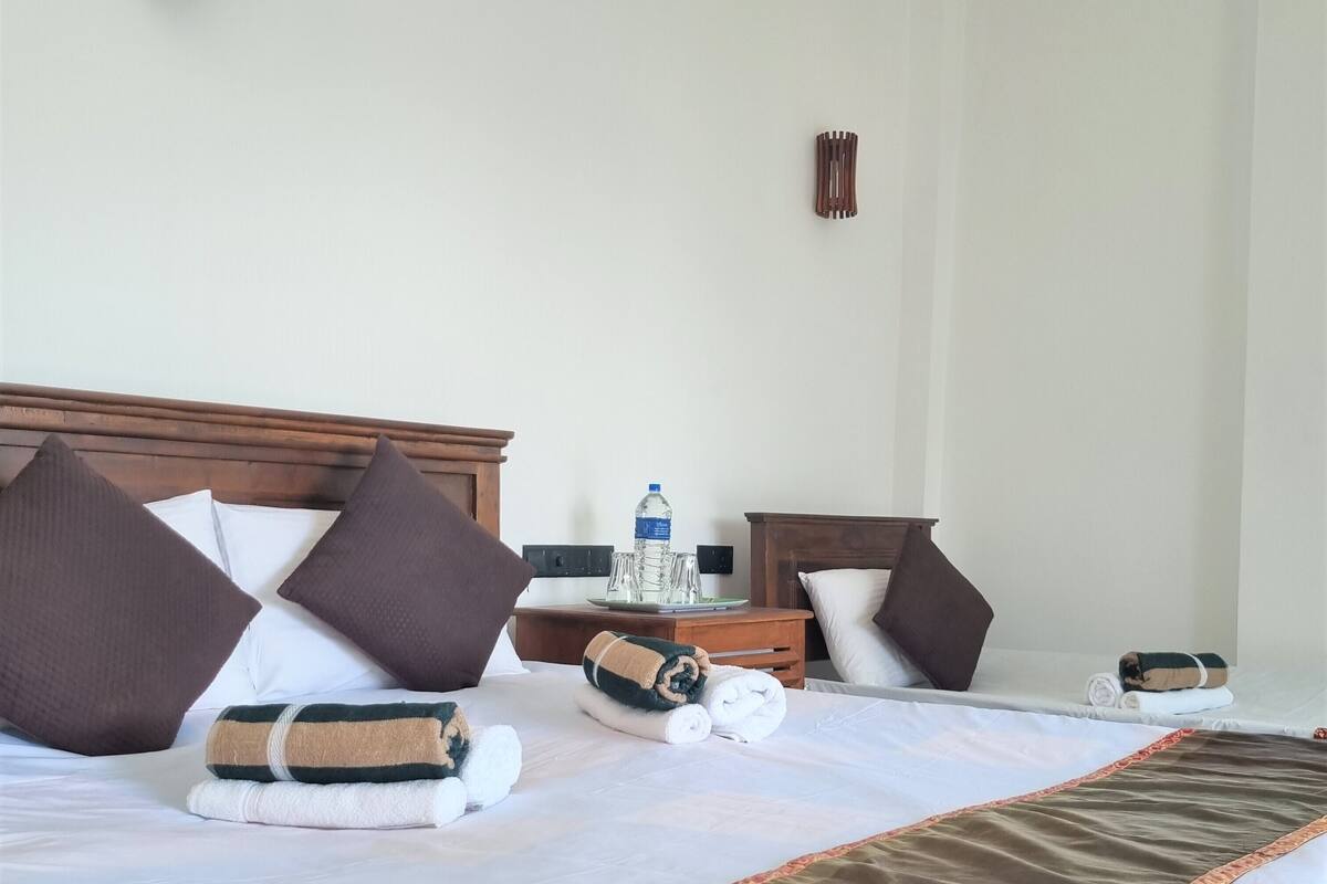 A neatly made bed with pillows, a water bottle, and a folded towel on a wooden headboard.