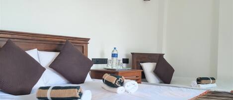 A neatly made bed with pillows, a water bottle, and a folded towel on a wooden headboard.