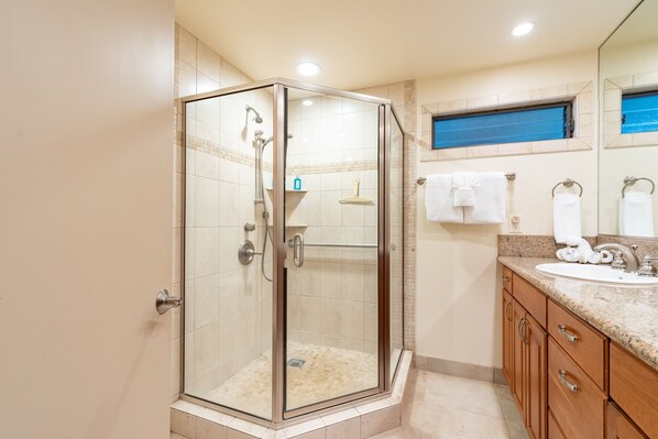 A modern bathroom with a glass-enclosed shower, a sink with a vanity, and a mirror above the sink.