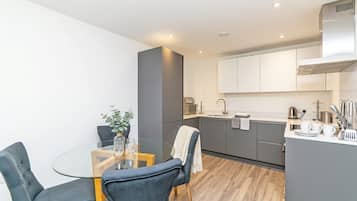 A modern kitchen with a central island, white cabinets, and a dining area with a glass table and chairs.