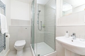 A modern bathroom with a glass-enclosed shower, a white toilet, and a sink with a mirror. - Free Parking | 2BR Apartment in Central Manchester (Manchester)