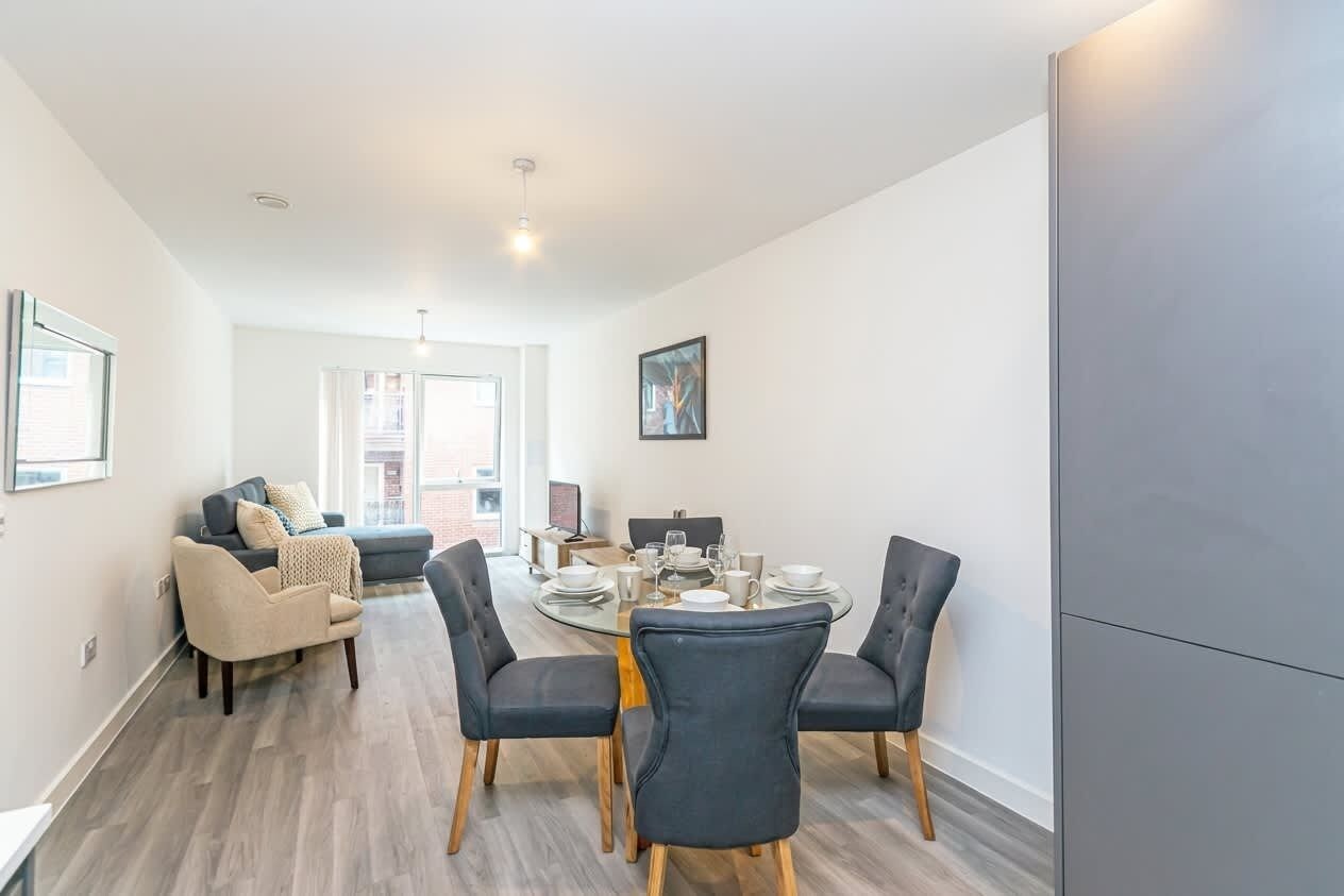 A modern living room with a dining area, a sofa set, and a dining table with chairs.