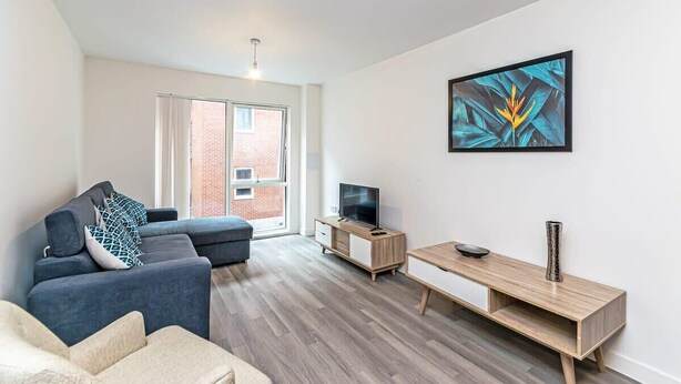 A modern living room with a sofa, TV stand, and artwork on the wall. - Central Manchester 2BR Apartment + Free Parking (Manchester)