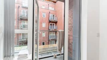 A balcony with a view of a brick building, a white towel, and a mug on the floor.