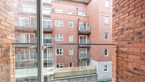 A multi-story residential building with brick facades, balconies, and a visible ground floor entrance. - Central Manchester 2BR Apartment + Free Parking (Manchester)