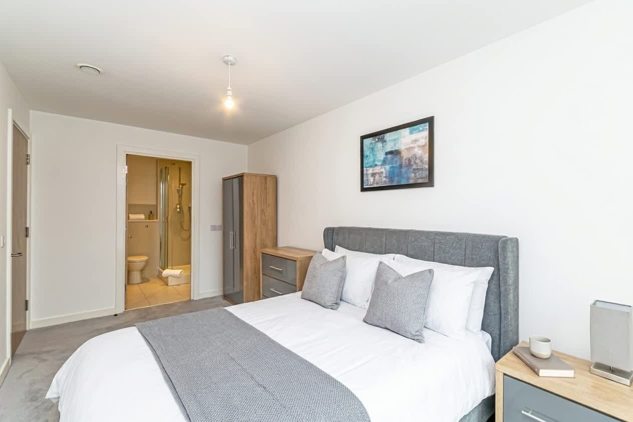 Une chambre à coucher moderne avec un lit, une table de chevet et une vue sur la salle de bain.