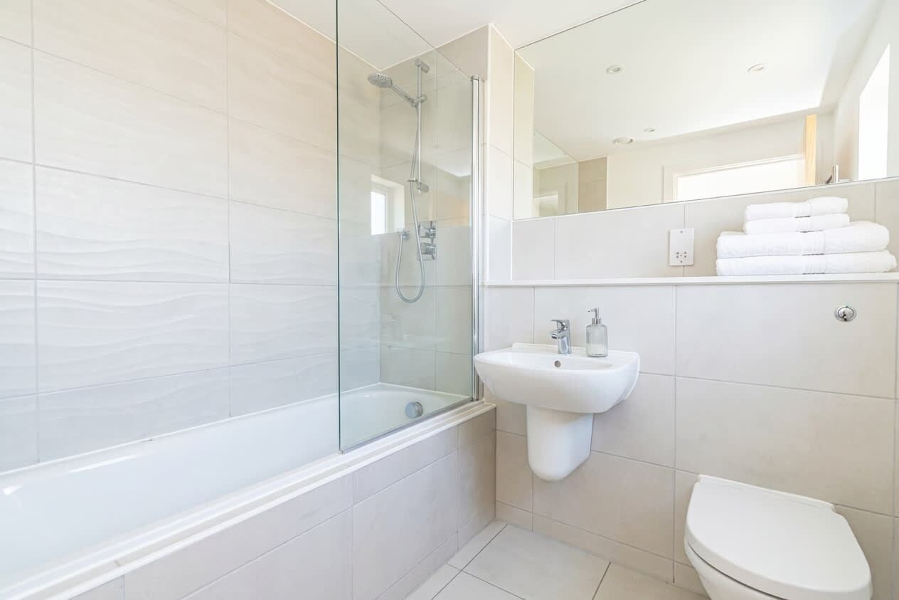 A modern bathroom with a glass-enclosed shower, a white sink, and a toilet.
