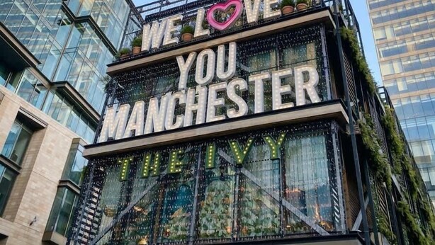 Un bâtiment sur lequel est affiché un panneau portant l’inscription « NOUS AIMONS MANCHESTER » et un symbole en forme de cœur.