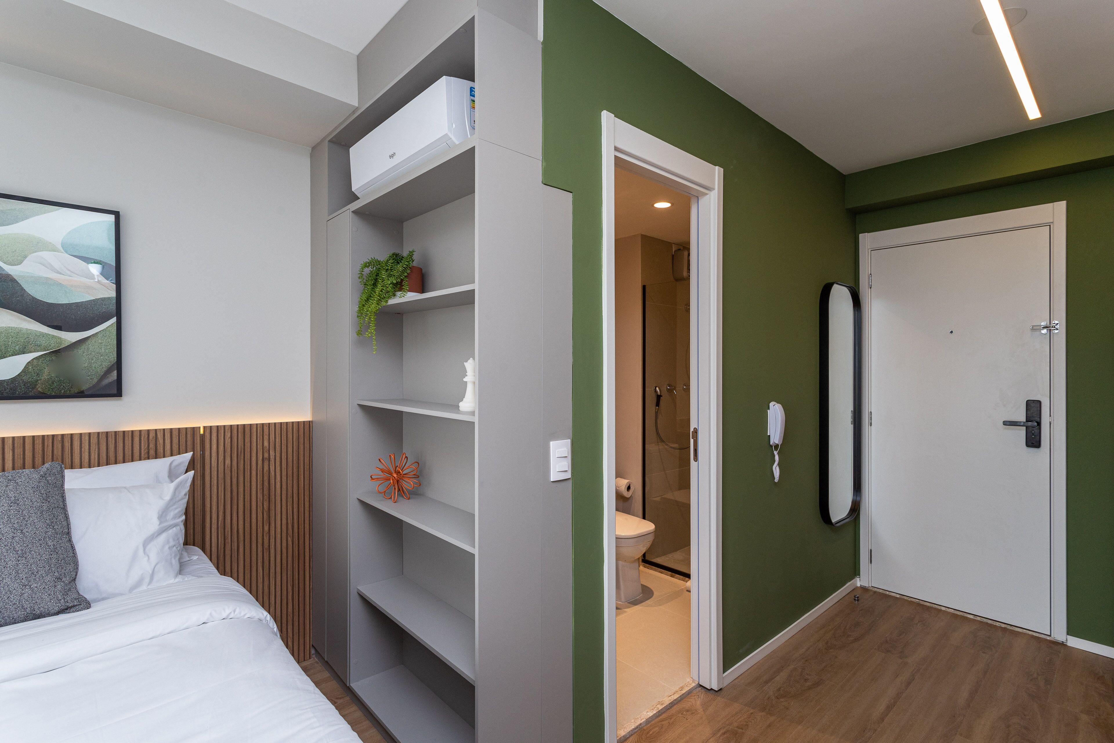 A modern bedroom with a bed, a built-in wardrobe, and a bathroom visible through an open door.