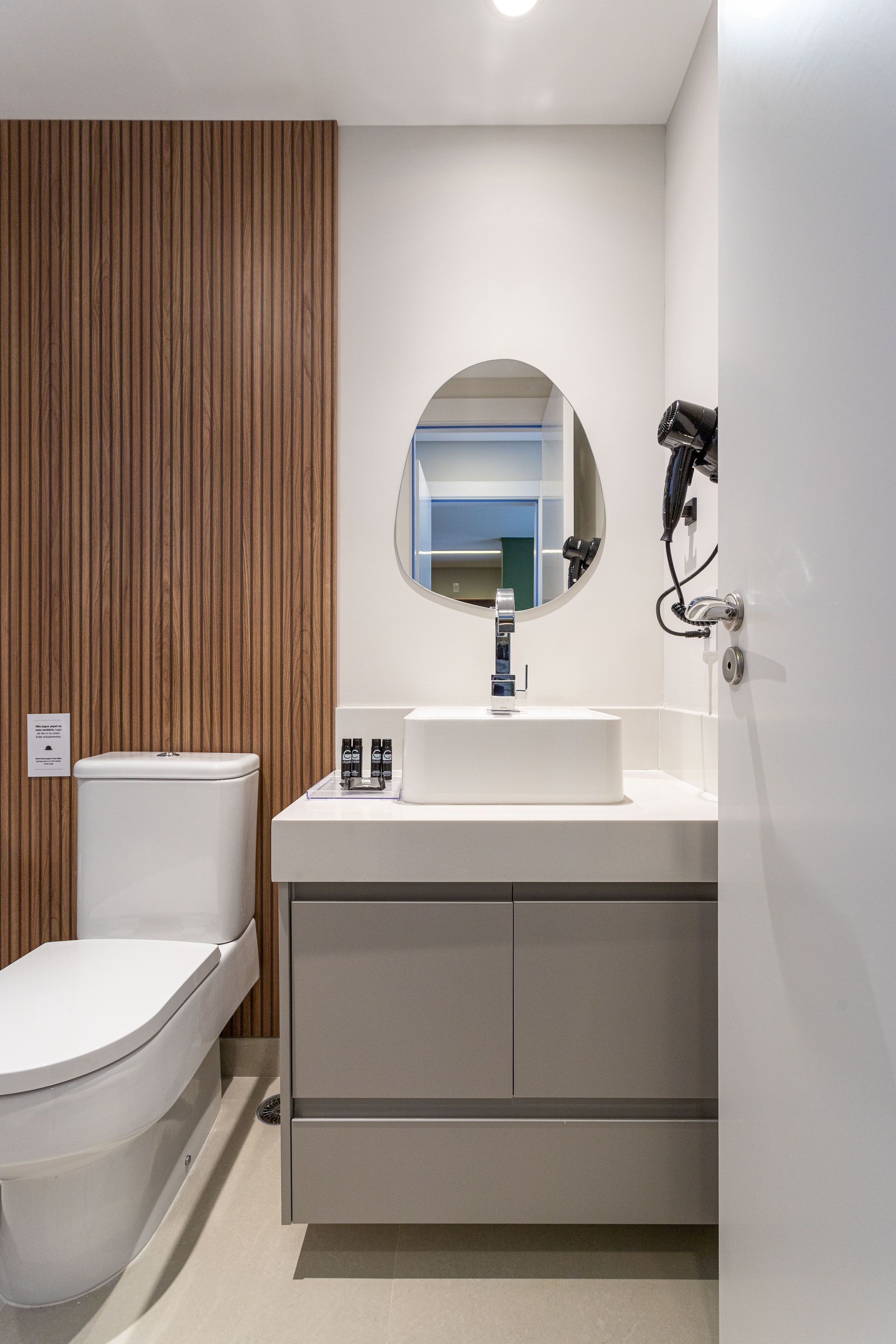 A modern bathroom with a toilet, sink, and mirror.