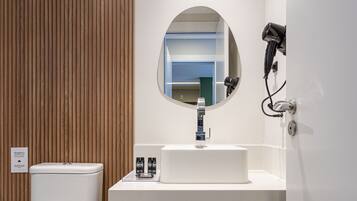Un baño moderno con inodoro, lavamanos y espejo.