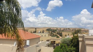 Un barrio residencial con edificios, cielo despejado y campos lejanos.