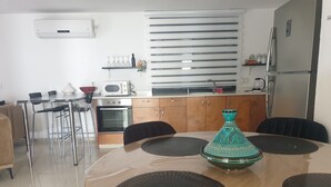 Una cocina moderna con zona de comedor, que presenta una mesa redonda con individuales negros, un jarrón decorativo y un microondas.