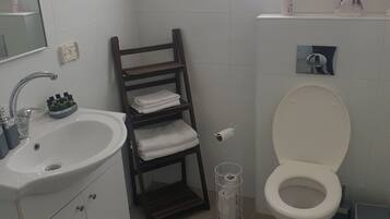 Un baño con lavamanos, espejo, toallero, inodoro y ventana.