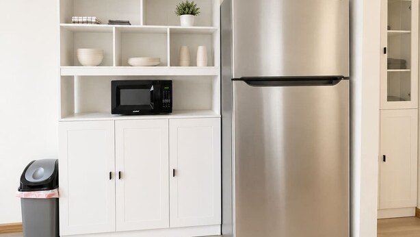 A kitchen with a stainless steel refrigerator, white cabinets, a microwave, and a trash bin. - Stand Rock Studios in Wisconsin Dells! (Wisconsin Dells)