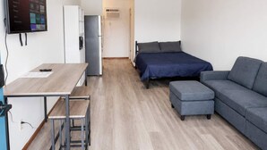 A compact room with a bed, a sofa, a desk, and a TV mounted on the wall. - Stand Rock Studios in Wisconsin Dells! (Wisconsin Dells)