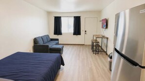 A hotel room with a bed, a sofa, a small table with stools, a TV, and a refrigerator. - Stand Rock Studios in Wisconsin Dells! (Wisconsin Dells)