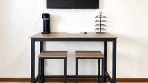 A small, modern kitchenette with a coffee maker, a flat-screen TV, and a metal rack. - Stand Rock Studios in Wisconsin Dells! (Wisconsin Dells)