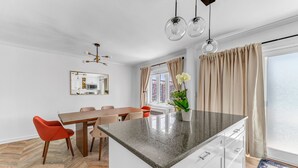 Una cucina moderna con isola centrale, pavimento in legno a spina di pesce e zona pranzo con sedie rosse.