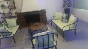 Ett vardagsrum med en öppen spis i sten, två soffor, ett soffbord och en prydnadsväxt.