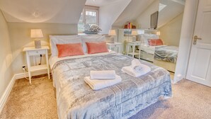 Une chambre à coucher avec un lit, des tables de chevet, un bureau et une chaise.