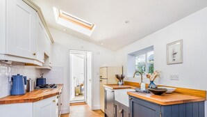 A modern kitchen with white cabinets, a wooden countertop, and a skylight. - Charming Downland Cottage - Pass the Keys (Chichester)