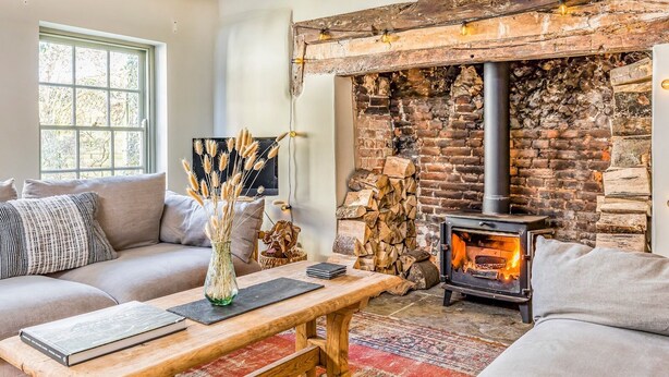 A cozy living room with a fireplace, a sofa, a coffee table, and a window. - Charming Downland Cottage - Pass the Keys (Chichester)