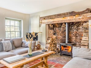 A cozy living room with a fireplace, a sofa, a coffee table, and a window.