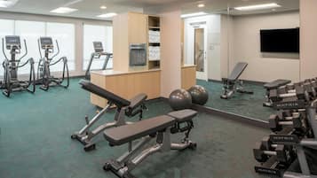 A gym with treadmills, a bench press, and dumbbells.