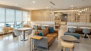Un hall d’hôtel moderne avec un canapé, des tables rondes et des chaises.