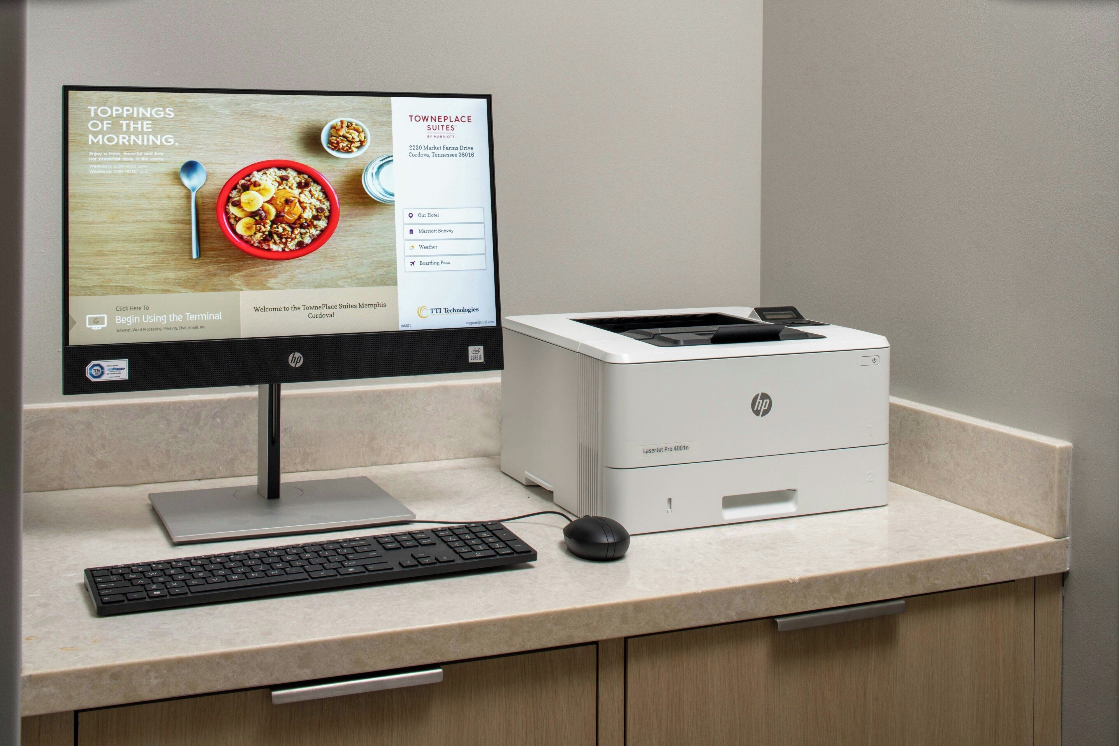 Una computadora de escritorio con un monitor que muestra un sitio web de hotel, un teclado, un ratón y una impresora HP sobre un escritorio.