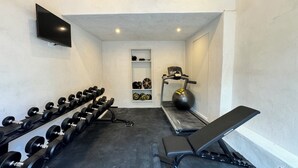 A gym with dumbbells, a bench, a treadmill, and a punching bag. - B&B Maison Gigi (La Garde-Freinet)
