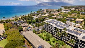 A coastal hotel with multiple buildings, solar panels, and a view of the ocean. - Ocean View Condo in the Heart of Kihei! (Kihei)