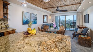A spacious living area with a large island, dining table, and comfortable seating. - Ocean View Condo in the Heart of Kihei! (Kihei)