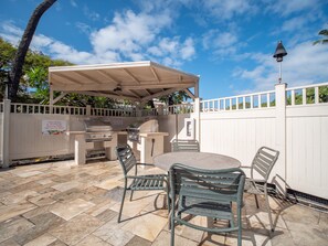 An outdoor patio with a grill, seating, and a covered area.