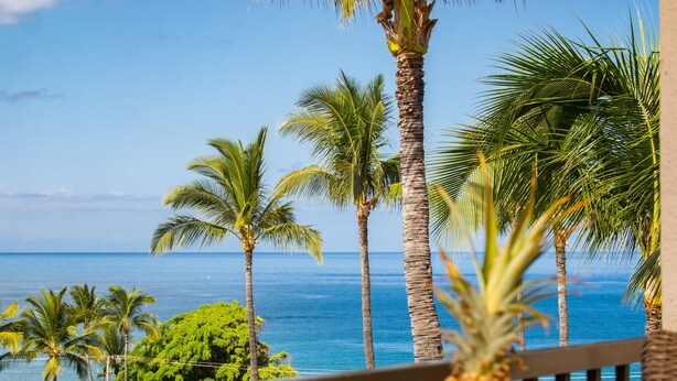 A balcony with a view of the ocean and palm trees. - Ocean View Condo in the Heart of Kihei! (Kihei)
